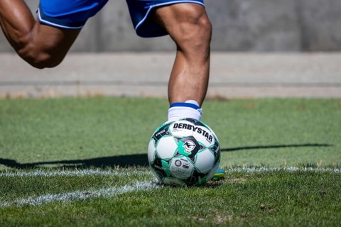 A soccer player kicks a corner kick with the DERBYSTAR BRILLANT APS 3RD LIGA, the official game