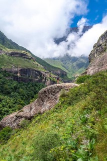 Female hiker standing in front of landscape with mountains and fog, Drakensberg National Park,
