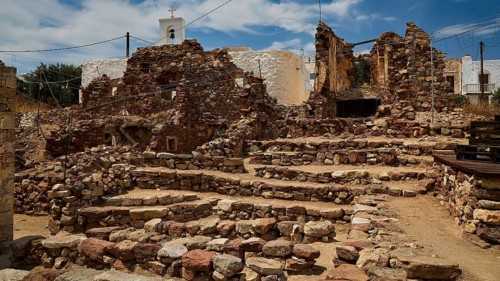 Old brick ruins with a small church in the background under a blue sky, Kastro, old castle above