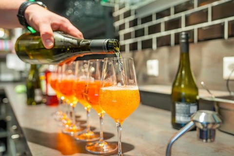 A drink is poured into a series of aperitif glasses at a bar, Cafe Kuh, Deckenpfronn, Germany