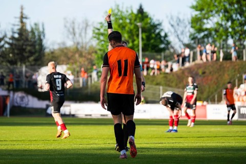 Referee showing a yellow card to a soccer player during a football match in a stadium in Glogow,