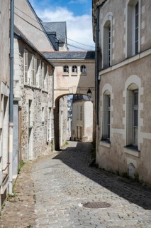Narrow, sunlit alley with historic cobblestones and historic stone buildings, dominated by an