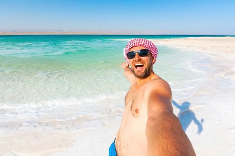 Happy male traveler tourist taking a smartphone selfie at the Dead Sea in Jordan after swimming in