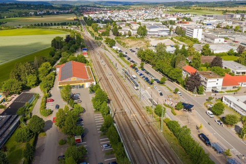 A general view shows rails, buildings and a city surrounded by green countryside, inauguration of