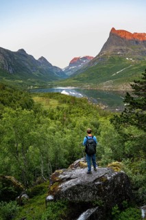 Young man jumping from stone to stone in water, picturesque mountain landscape in the Innerdalen