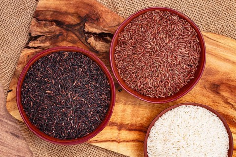 Set of red and black and white rice, in a bowl, on a wooden surface, rustic style, top view