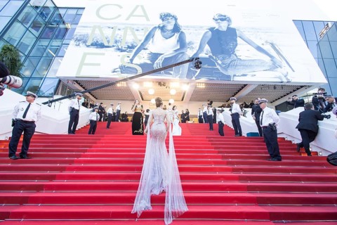 Woman in a long glittering dress walks up the stairs at the opening gala and premiere of La Vénus