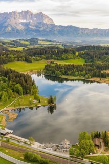 Panoramic view of quiet lake surrounded by mountains, Schwarzsee circular trail, Kitzbühel, Austria