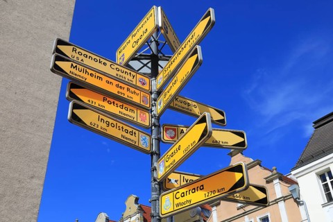 Street sign on the market square of Opole, Opole, Poland, showing distances to various partner