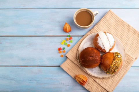 Maritozzo traditional Italian bun dessert, cup of coffee, on blue wooden background with orange