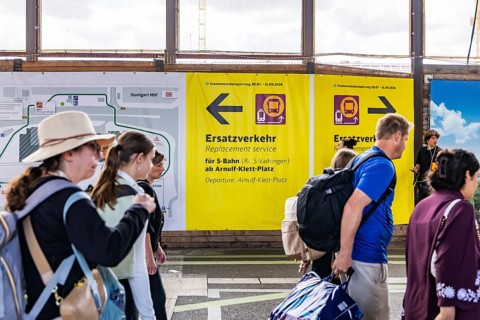 Travelers in the train station. Passengers at Stuttgart Central Station. Signage for alternative