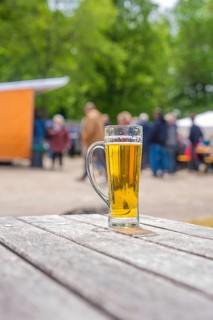 A glass of beer on an outdoor wooden table, with blurred background, Father's Day, Forest Festival,