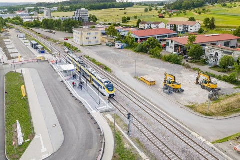 Railway station with yellow train, surrounded by buildings and machinery, view from the air,