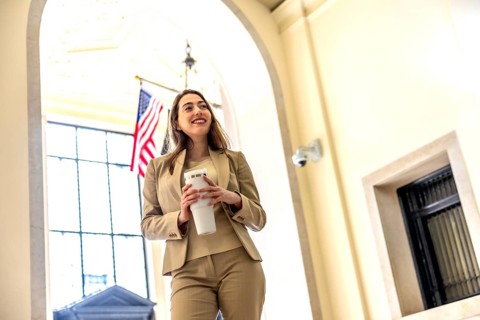 Young businesswoman standing inside a building lobby, confidently looking up and smiling while