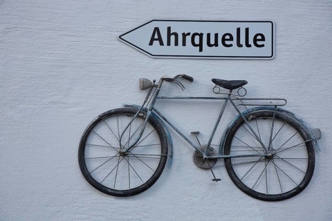 Signpost to the Ahr spring and old bicycle as decoration, inscription, signpost, house facade, Ahr