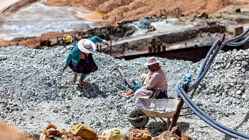 Two people in traditional clothing work with rocks on a tailings heap, The Potosi Silver Mines on