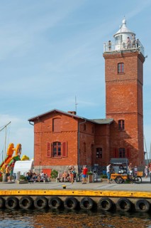 Red brick lighthouse at the harbour with people at the water, lighthouse, Darlowo, Rügenwalde,