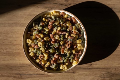 Top view of colorful number shaped pasta in a ceramic bowl, under soft lighting with a distinct