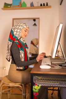 Veiled Arab girl at home computer, working from home. Modern Arab young woman with new technologies