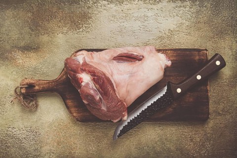 Raw pork knuckle, on a wooden chopping board, close-up, top view, no people