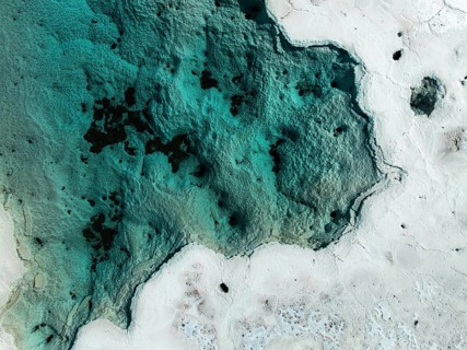 An aerial view of the vibrant salt ponds in La Puna, Argentina, showcasing striking turquoise and