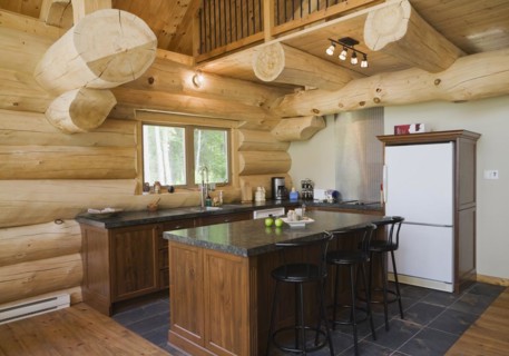 Island with dark grey granite countertop and black stained wooden bar stools in kitchen with