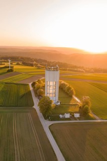 Rural landscape at sunset with water tower surrounded by green fields and a quiet, peaceful