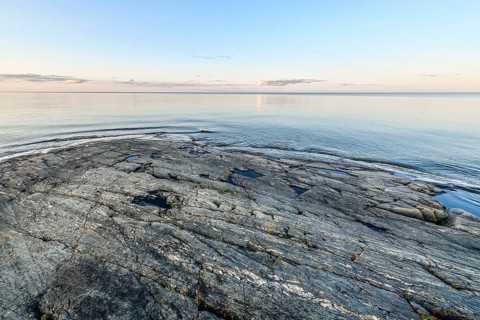 Far-reaching view of the quiet lake Vänern with gently sloping granite rocks archipelago under calm