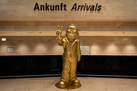 A giant golden garden gnome greets travelers and visitors in the arrivals area of the new Terminal