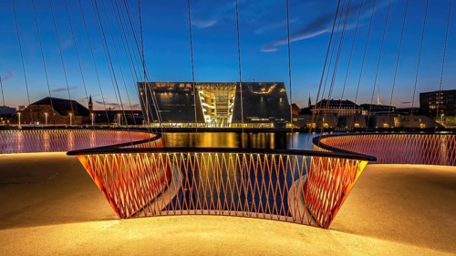 Abendszene mit beleuchteter Brücke und modernem Gebäude im Hintergrund, Kopenhagen, Dänemark,