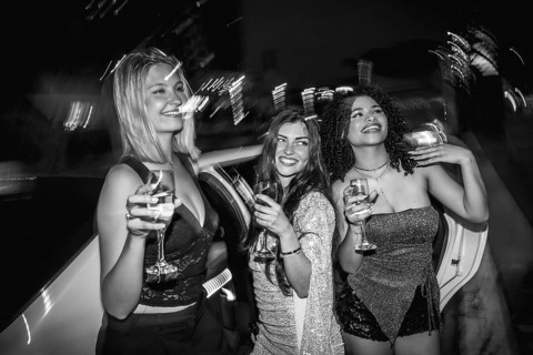 Three happy young women traveling in a luxurious limousine, celebrating a special occasion,