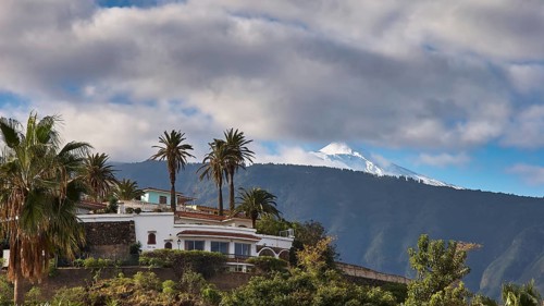 Puerto de la Cruz, White House with palm trees in front of a snow-capped mountain and clouds, Teide