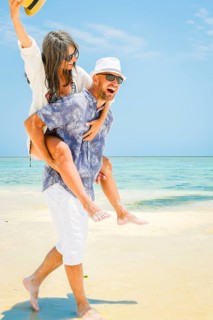 Carefree young man woman piggyback ride walking along turquoise ocean sand beach global tropical