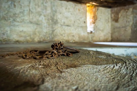 Close-up of authentic iron chains and shackles display in underground slave chamber in Mkunazini,