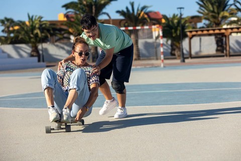 A joyful scene of a Down syndrome teenager participating in outdoor sports with family on a sunny
