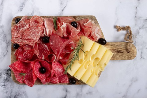 Assorted meat, appetizer, prosciutto, salami and ham, with maasdam cheese and olives, on a wooden