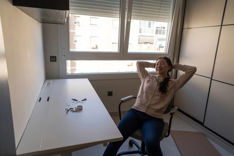 A young Asian woman enjoys a moment of satisfaction after assembling a white desk at home. This DIY