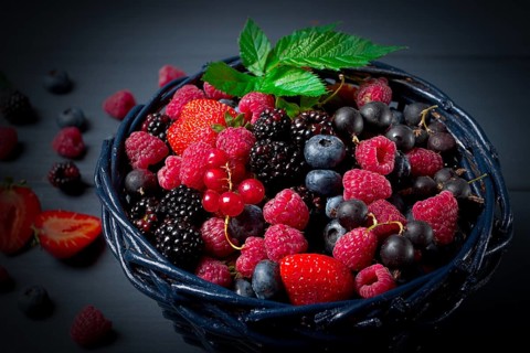 Mix of fresh berries, in a basket, on a wooden gray table, no people, top view