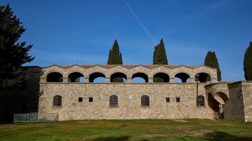 Monastery of Our Lady of Mount Filerimos, historic stone building with arches under a blue sky,