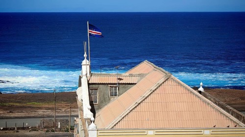 View from above of a building, City Hall, with a terracotta roof against the deep blue ocean with a