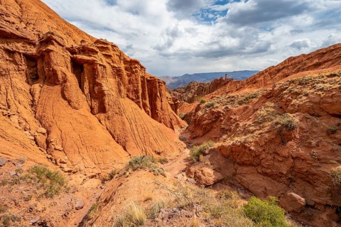 Eroded mountain landscape with sandstone cliffs, canyon with red and orange rock formations,
