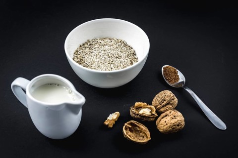 Oatmeal in a cup and winged walnuts and sugar black background. Oatmeal recipe with walnuts,