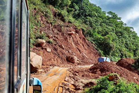 A landslide blocks the road, the bus navigates through the rough, red terrain, bus ride from La Paz