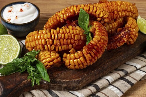 Corn ribs, with cream sauce, spices and lime, appetizer, on a wooden cutting board, homemade, no