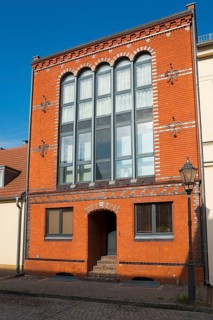 Historic building with brick façade and large windows under a clear sky, old town island of Werder
