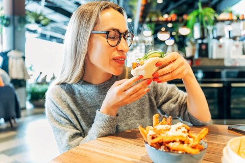 Stylish Woman Enjoying a Freshly Made Bao Bun at a Trendy Urban Restaurant