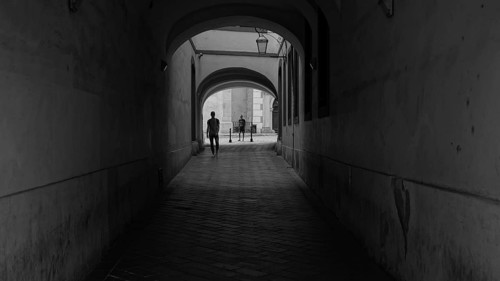 Dark passageway with people heading for a bright exit, monochrome street scene from Bratislava,