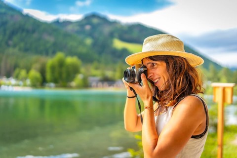 Tourist taking pictures with vintage camera of the beautiful landscape at lake dobbiaco in the