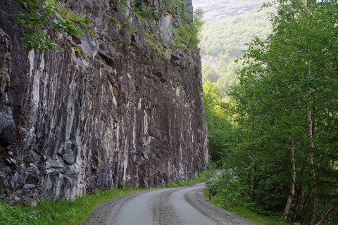 A narrow path that leads along a high rock face and dense forest, Eikesdalen. Aursjövegen, More og