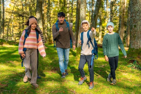 Teenage boy pointing ahead while trekking with the family at forest in a sunny day of autumn